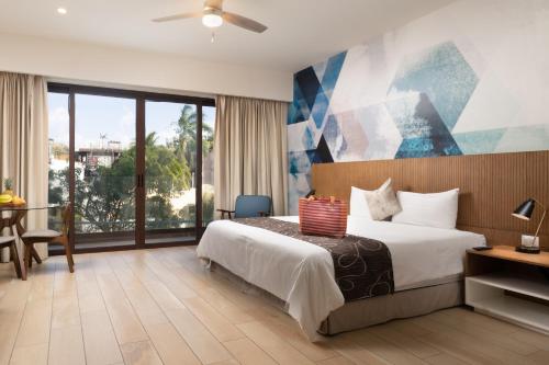 a hotel room with a bed and a large window at Tú Paraiso Privado- Lahun Suites Playa del carmen in Playa del Carmen