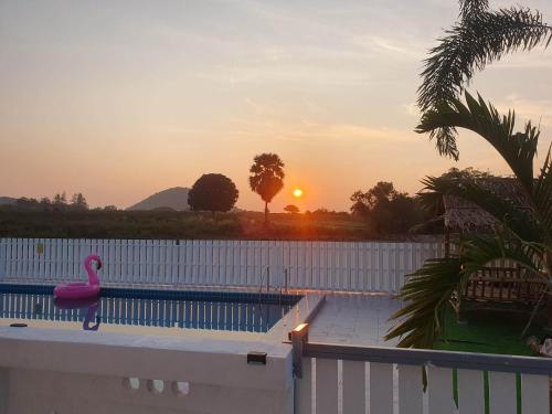 - une piscine avec un flamingo rose au coucher du soleil dans l'établissement S&F villa, à Sam Roi Yot