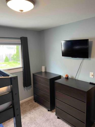 a bedroom with a dresser and a tv on the wall at Cute home near EMU and U of M in Ypsilanti