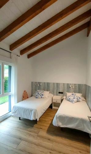 two beds in a room with wooden floors at La Flor de Agua in Torielló