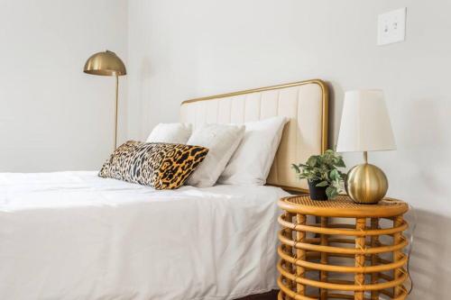 a bedroom with a white bed with a gold lamp and a table at Bright + New - Fire Pit - Hammock - 3 bd in Raleigh