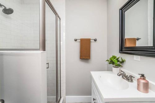 a bathroom with a sink and a shower with a mirror at Bright + New - Fire Pit - Hammock - 3 bd in Raleigh