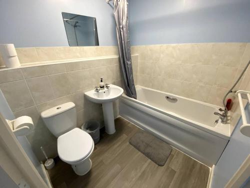 a bathroom with a toilet and a sink and a tub at Modern Penthouse in Wellingborough