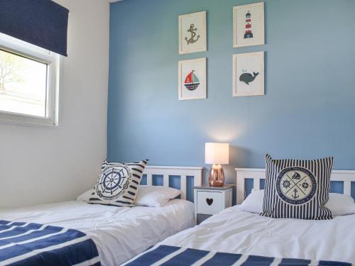 two beds in a bedroom with blue walls at Hectors House in Scratby