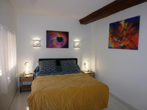 1 dormitorio con 1 cama y 2 cuadros en la pared en Le Scoubidou, en Perpiñán