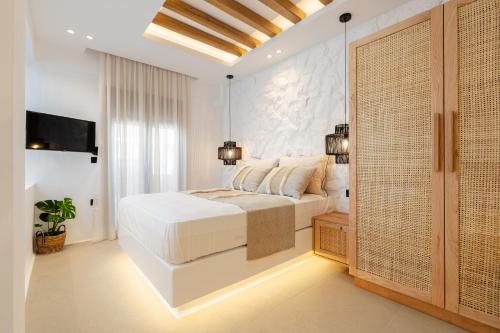 Habitación blanca con cama y TV en ElVirtus Suites, en Naxos Chora