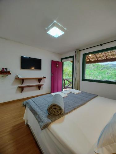 a bedroom with a large white bed with a window at Recanto Serra do Trovão in Ouro Preto