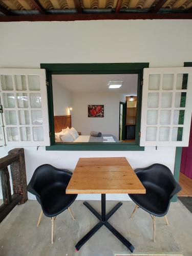 a table and two chairs in a room with a bedroom at Recanto Serra do Trovão in Ouro Preto