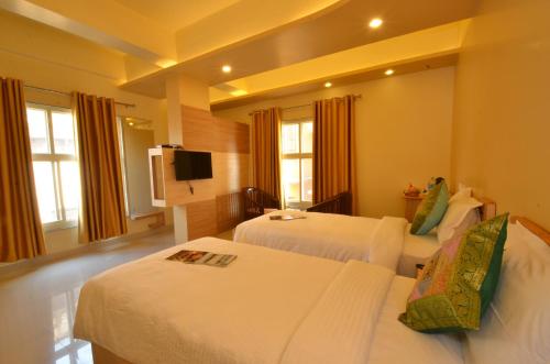 a hotel room with two beds and a flat screen tv at Hotel Banaras Haveli in Varanasi