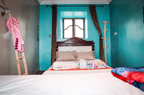Un dormitorio con una cama con paredes azules y una ventana en da housa hostel, en Tahliouine