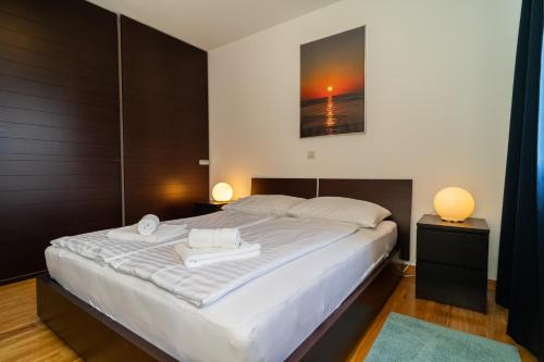a bedroom with a large white bed with two lamps at Apartment Cosmopolitan in Zadar