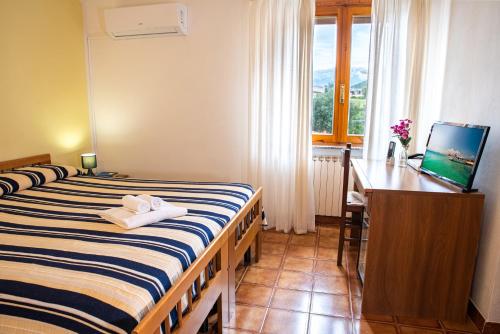 a bedroom with a bed and a desk and a television at Hotel L'Aragosta in La Caletta