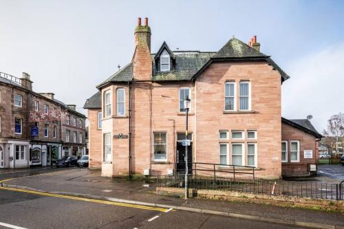 an old brick building on the side of a street at CASTLEBANK HOUSE FLATS, DINGWALL in Dingwall