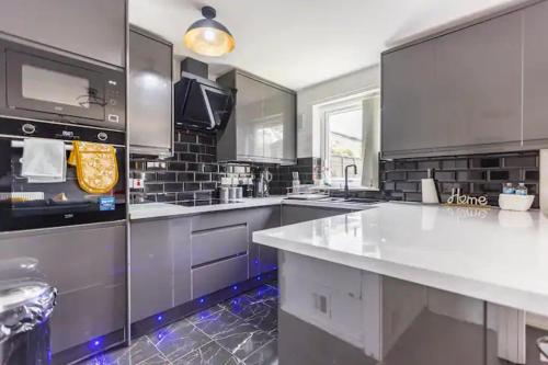 a large kitchen with a large white counter top at Mordenised 2 Bedroom House close to City Centre in Leeds