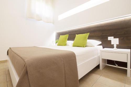 a bedroom with a white bed with green pillows at La Casina Di Borgagne in Borgagne