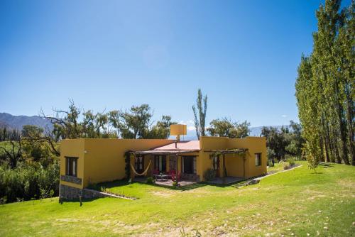 a small yellow house on a grassy field at La Pascana in Cachí