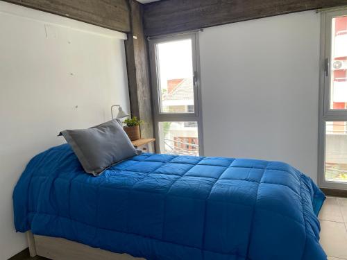 Cama azul en habitación con 2 ventanas en Sarmiento 430 en San Salvador de Jujuy