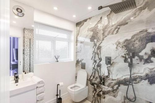 ein Bad mit einem WC und einer Marmorwand in der Unterkunft Queens Apartment ( Entire 2 bed apartment ) in Potters Bar