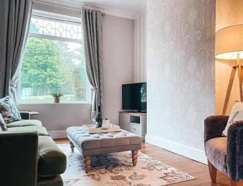 a living room with a couch and a tv at Beechwood Park by Solace Stays in Newport