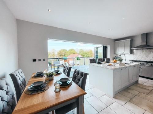 a kitchen and living room with a wooden table and chairs at Beechwood Park by Solace Stays in Newport