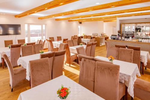 uma sala de jantar com mesas e cadeiras brancas em Hotel AirStar em Surčin