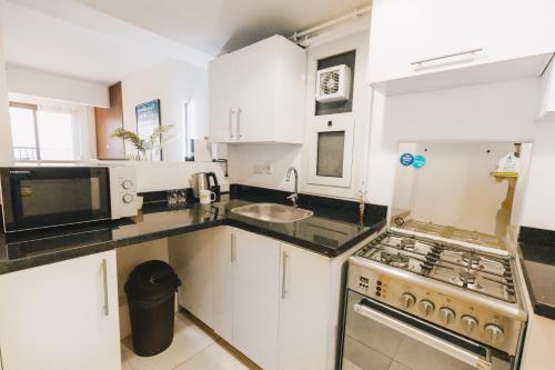 a kitchen with white cabinets and a stove top oven at LOFTS by Elegant Hospitality in Cairo