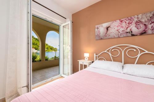 a bedroom with a bed and a large window at Apartments Mirjana Mljet in Prožura