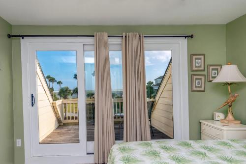 1 dormitorio con puerta corredera de cristal y balcón en 703 Spinnaker Beach House, en Seabrook Island