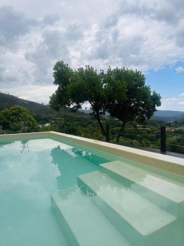 a blue swimming pool with a tree in the background at Britelo 1828 - Refúgio na Natureza in Ponte da Barca