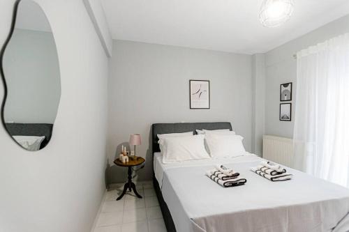 a white bedroom with a bed with two towels on it at Hermes Modern Apartment in Alexandroupoli