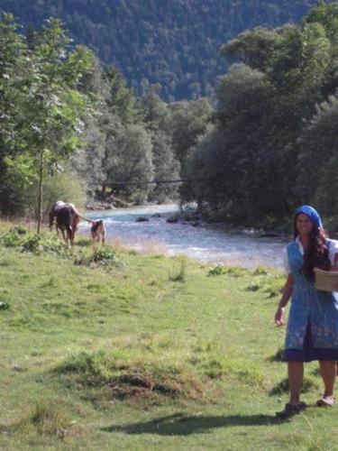 a woman standing in a field with a horse in the background at Apartmaji in Sobe Cuder in Soča