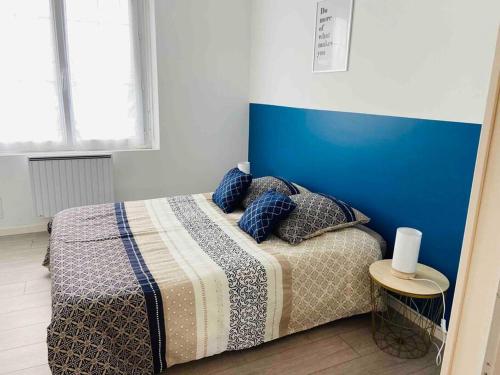 a bedroom with a bed with a blue headboard at L’escale Abbevilloise by H2C in Abbeville