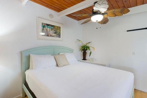 a bedroom with a white bed with a ceiling fan at Saylor's Bay in Key Colony Beach