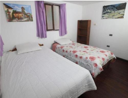 two beds in a bedroom with purple curtains at Pink Sheep Hostal in Cusco