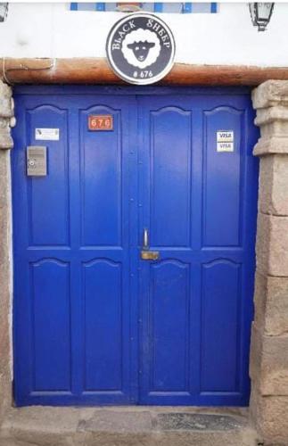 a blue door on a building with a sign above it at Pink Sheep Hostal in Cusco