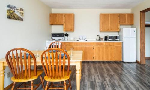 a kitchen with a table and chairs and a refrigerator at Hebridean Motel in Port Hood