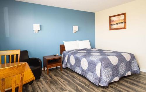 1 dormitorio con cama, escritorio y silla en Hebridean Motel, en Port Hood