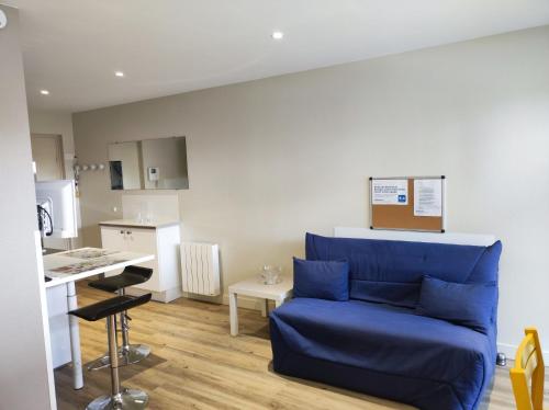 ein Wohnzimmer mit einer blauen Couch und einer Küche in der Unterkunft Studio des Marches de Bretagne in Fougères
