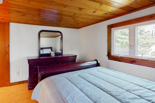 1 dormitorio con cama, tocador y espejo en Belmont Beach Cottage, en West Harwich