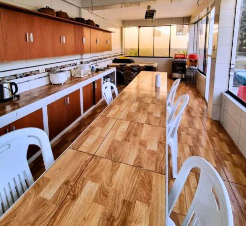 una gran cocina con una larga mesa de madera y sillas blancas. en Casa Campestre El Huerto en Ricardo Palma