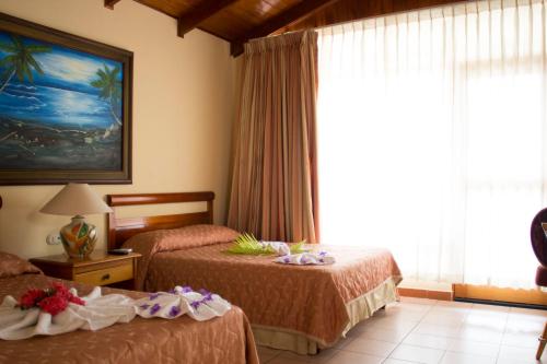 a hotel room with two beds and a window at Amapola Resort in Jacó