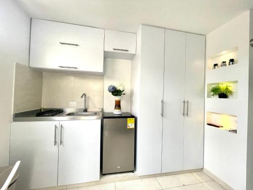 uma cozinha com armários brancos e um frigorífico de aço inoxidável em Aparta estudios nuevos Mubarak em Barranquilla