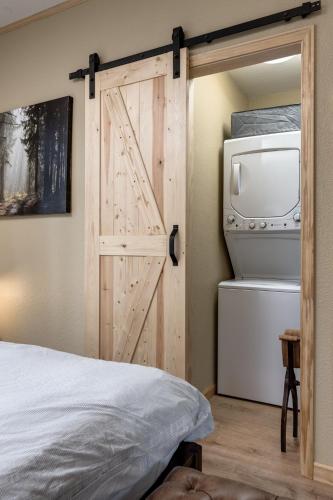 a sliding barn door in a bedroom with a washer and dryer at Little House in the Big Woods in Forest Ranch