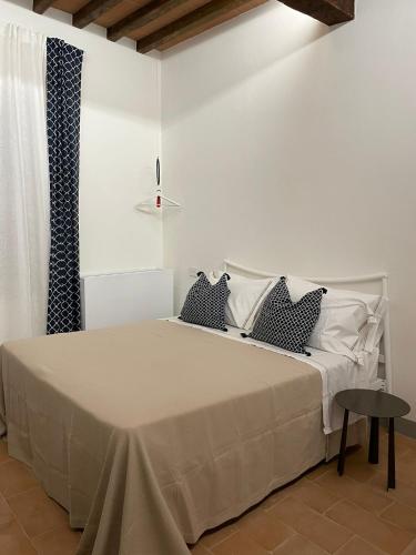 a white bedroom with a bed with black and white pillows at MontepulcianoLettings in Montepulciano