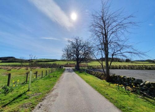 a dirt road next to a fence and a river at Strathken Cottage in Castle Douglas