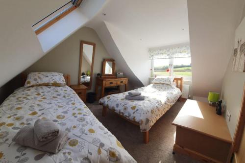 1 dormitorio con 2 camas y espejo en Strathken Cottage en Castle Douglas
