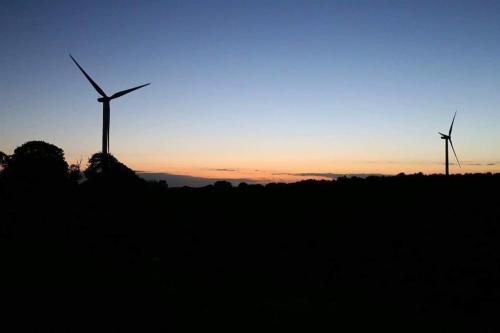 two wind turbines in a field at sunset at DOG FRIENDLY little bungalow with patio & private driveway in Kessingland