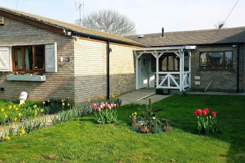 uma casa com um quintal com flores na relva em DOG FRIENDLY little bungalow with patio & private driveway em Kessingland