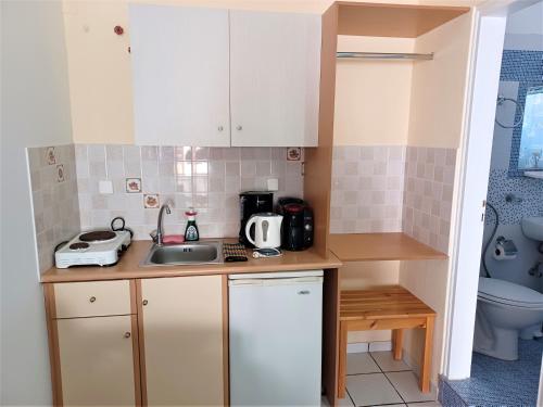 a small kitchen with white cabinets and a sink at Evelina Family Beach Pension a breath away from the Black Beach offer plenty of accommodation type to suit every traveler's needs-Economic Rooms-Thematic Rooms-Design Rooms-Kitchenette Rooms-Studios-Small Apartments in Perissa