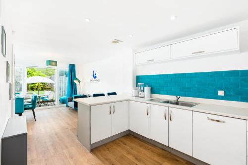 a kitchen with white cabinets and a blue accent wall at Spacious Group House for Contractors & Families - Ensuites, Parking & Netflix by DreamyPads in Bristol